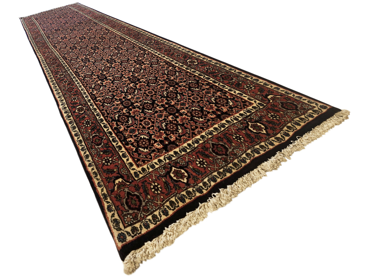 Bidjar runner rug in dark red and beige with ornate central motif and fringe trim.