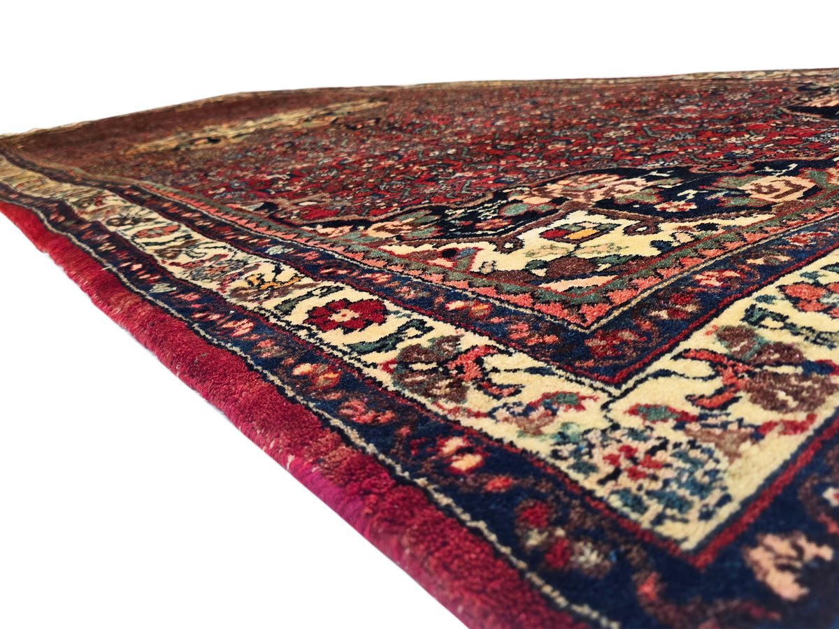 Bidjar rug corner view, red ground with cream lattice motifs and navy trim, short fringe