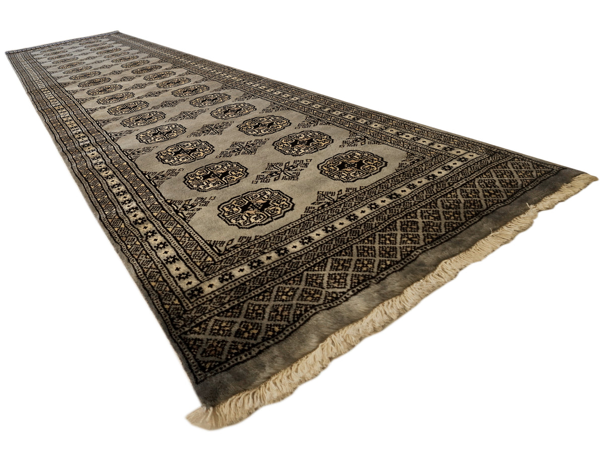 Flatwoven rectangular rug with repeating corner-and-border motifs and textured fringe trim