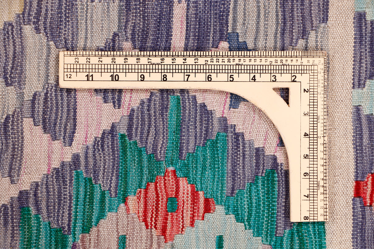 Kilim rug edge with ruler measuring tape across a multicolor geometric field