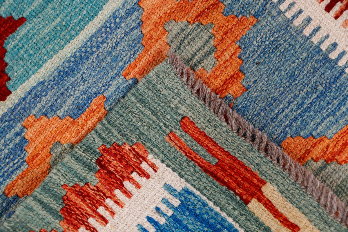 Kilim rug corner with tasseled fringe and geometric bands in blue, orange, and red