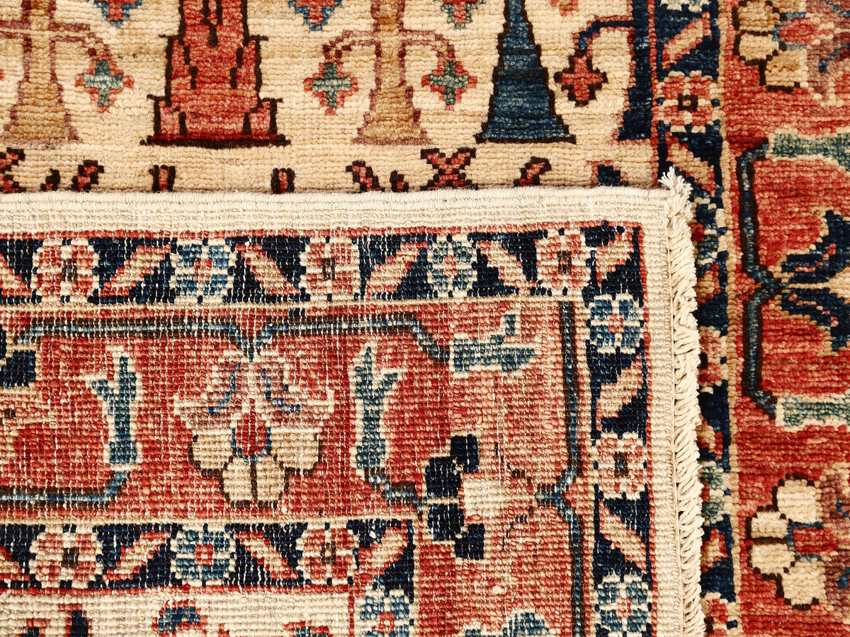 Corner close-up: red rug with beige field, blue border pattern, and fringe