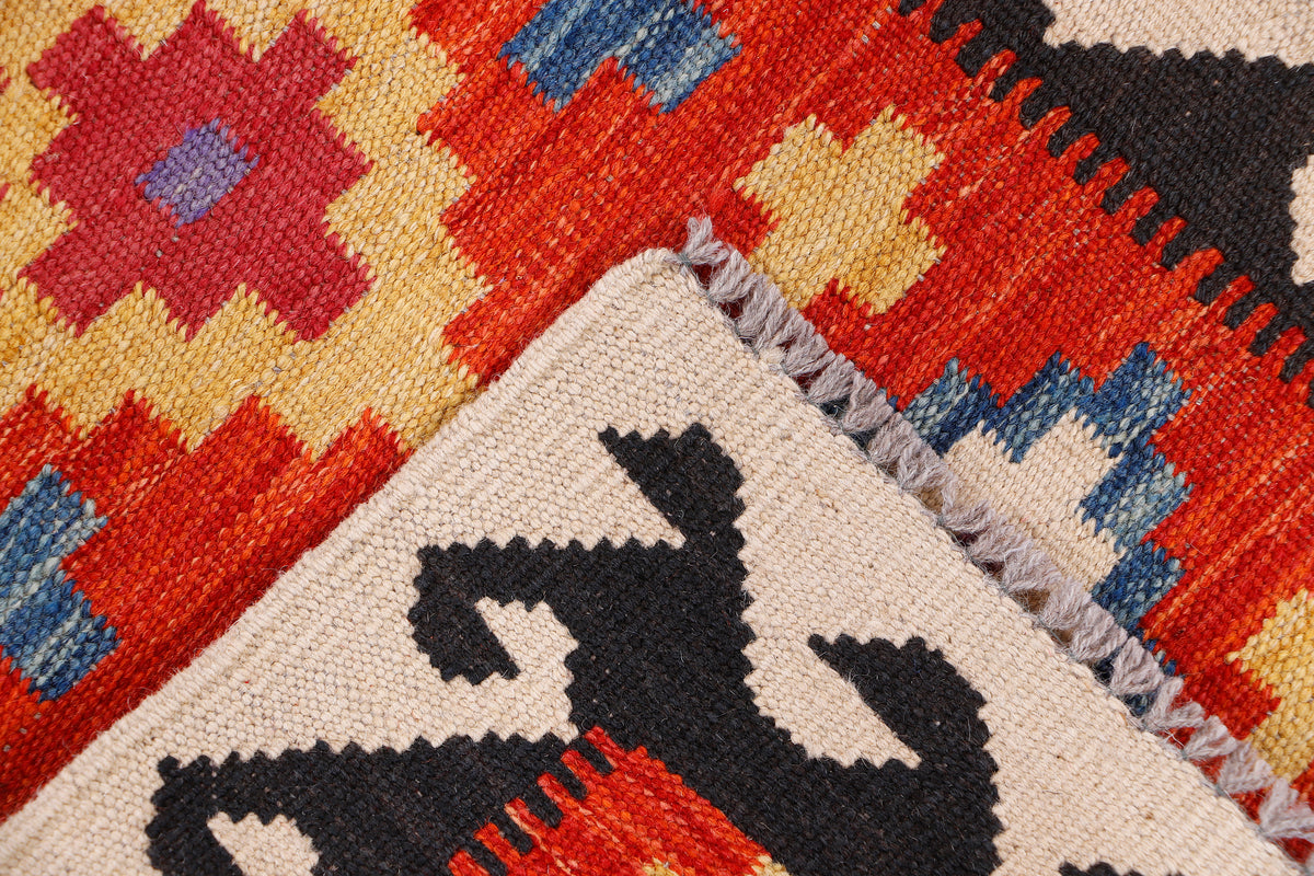 Cream kilim rug corner with red, blue, and black diamond motifs and fringe