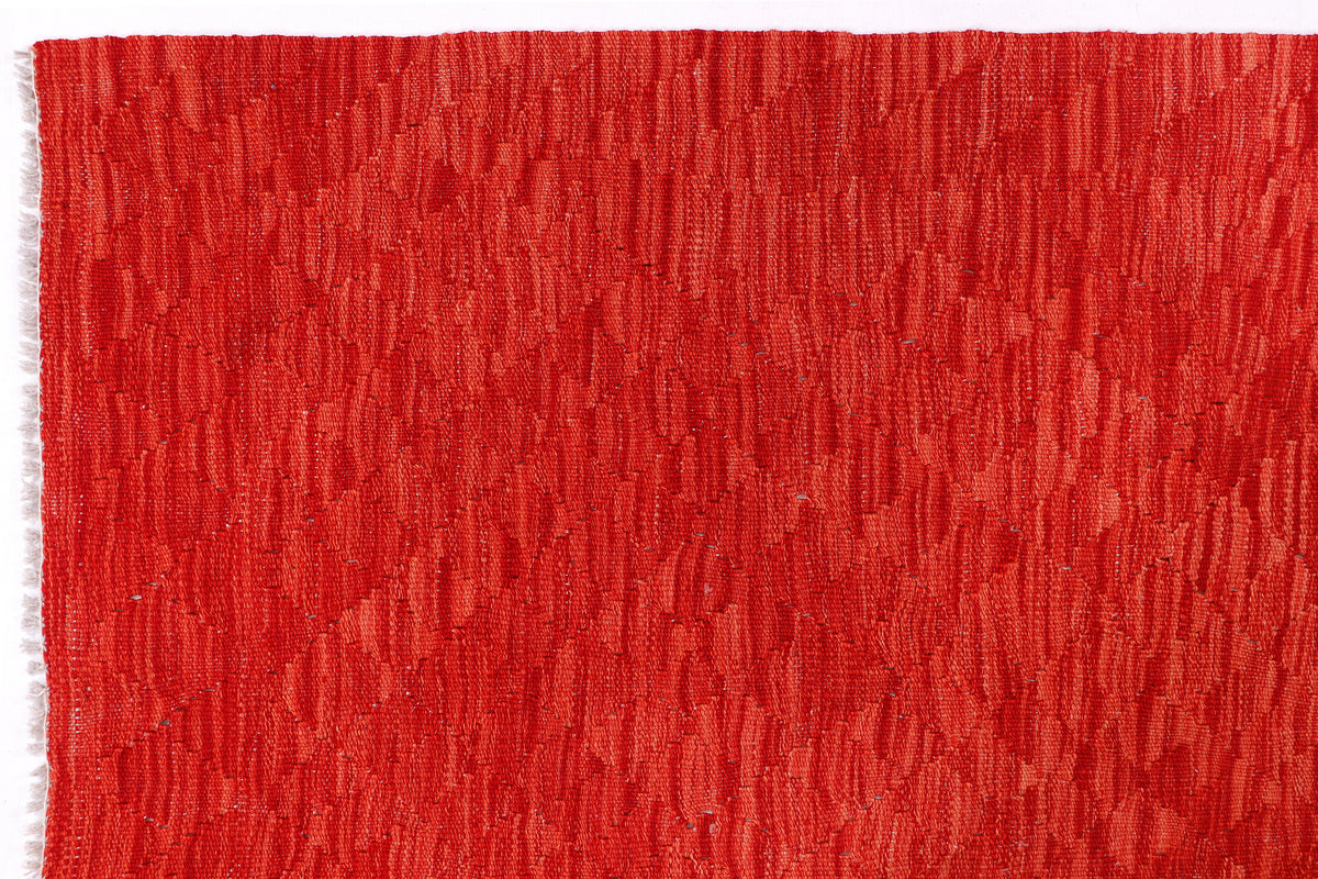 Red kilim rug close-up with dense flat weave and subtle tonal pattern
