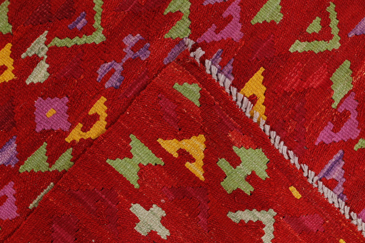 Crimson mosaic red kilim rug corner with geometric pattern and short fringe