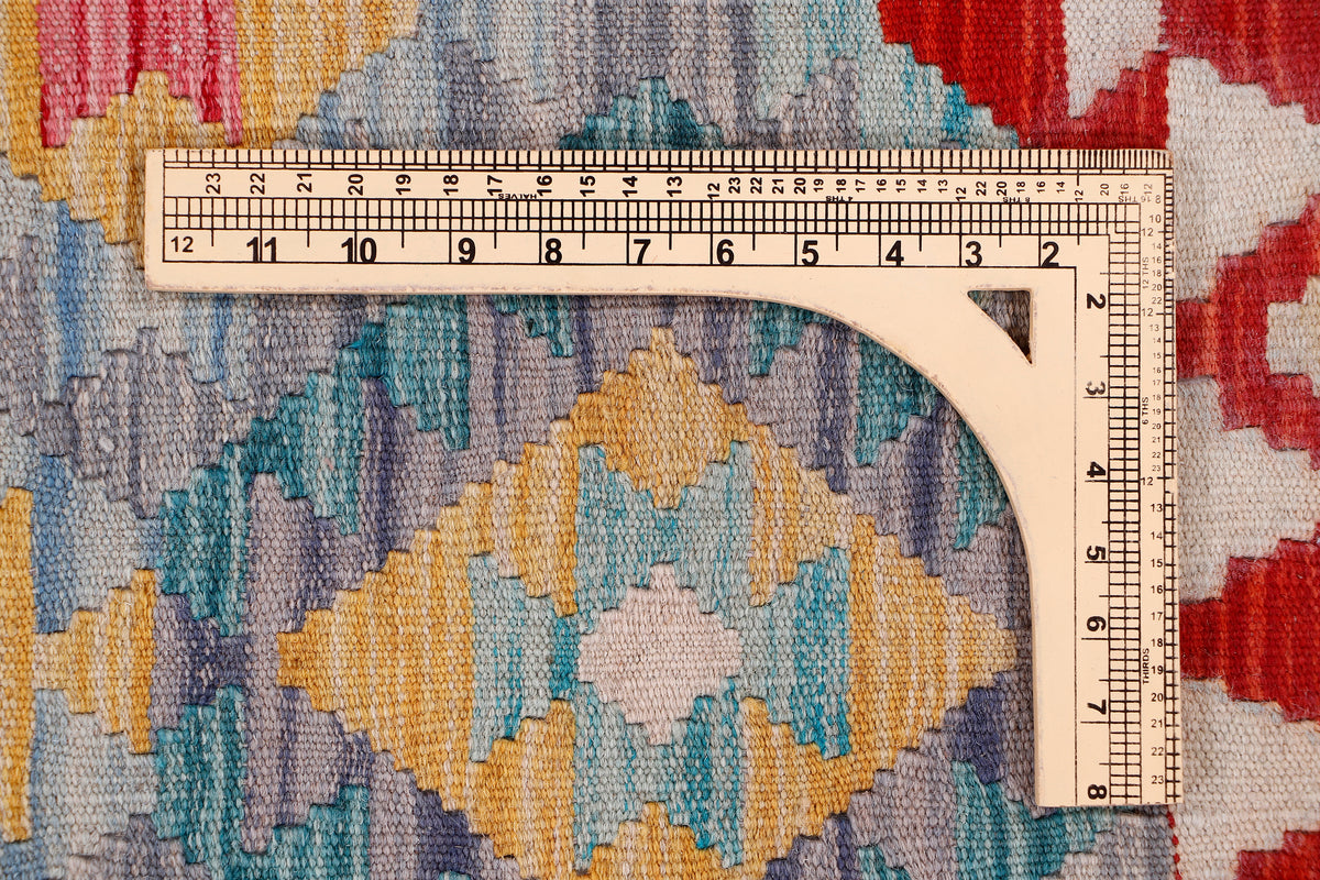 Kilim rug detail with measuring tape along border; geometric red, blue, yellow motifs