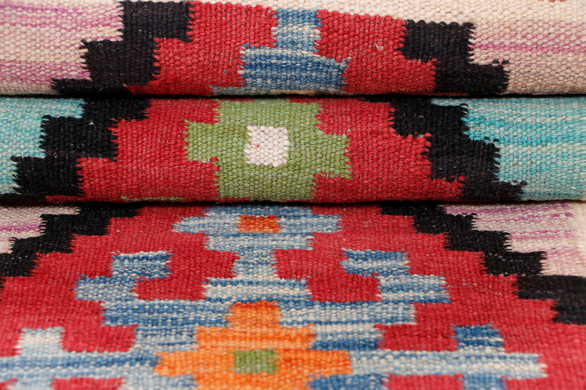 Kilim rug close-up showing central multicolor diamond medallion on cream background