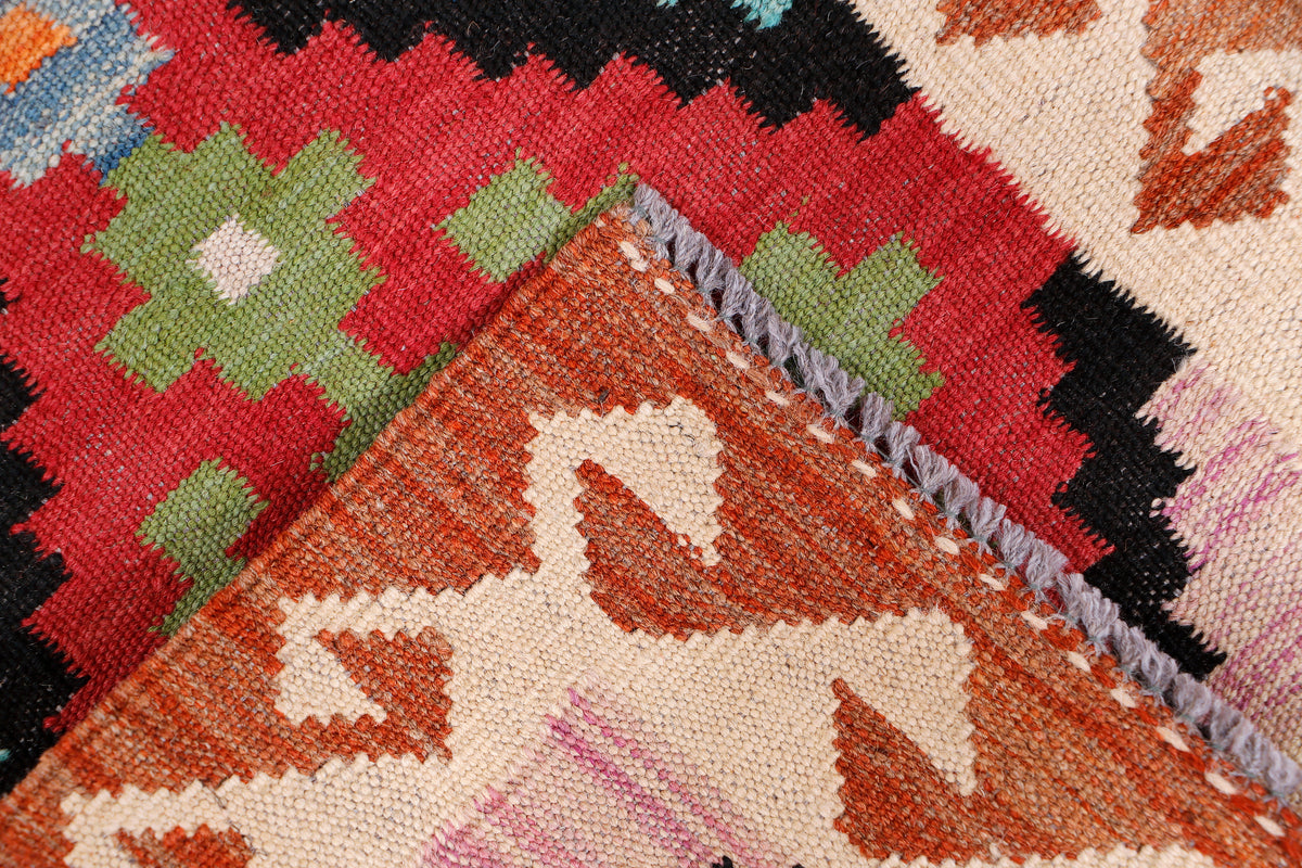 Kilim rug corner with red, green, blue geometric pattern and short fringed edge