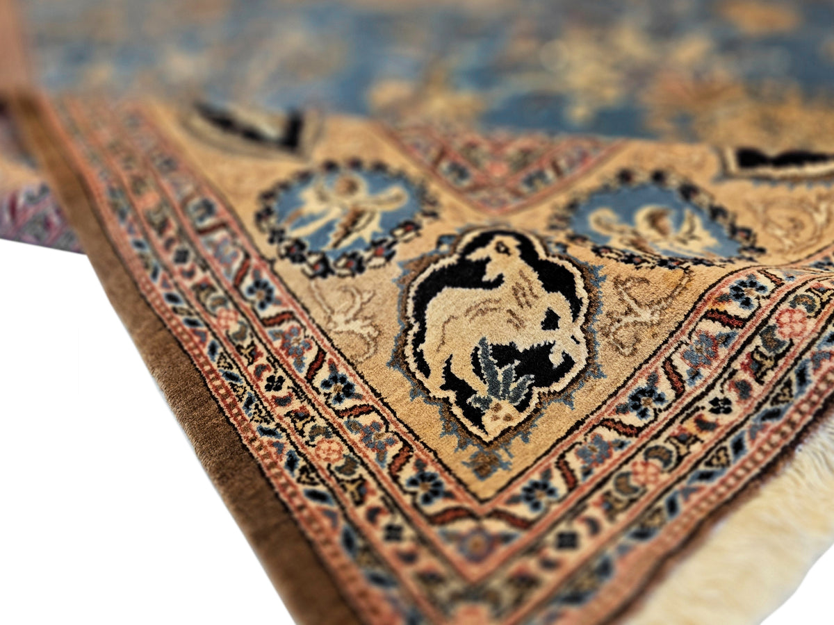 Close-up of blue rug with tan animal medallion and detailed border