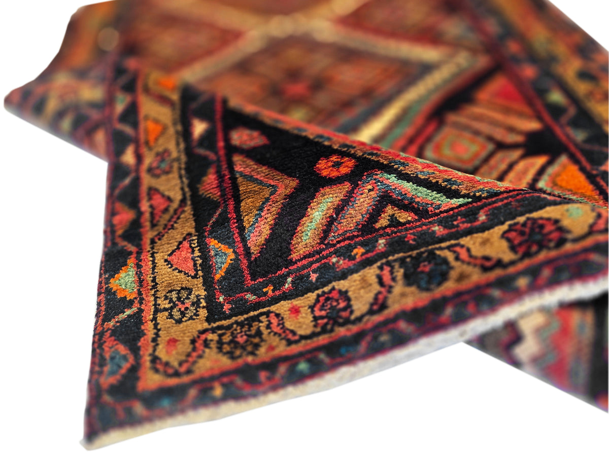 Hamedan rug close-up of diamond medallions in rust, cream, and blue-black accents