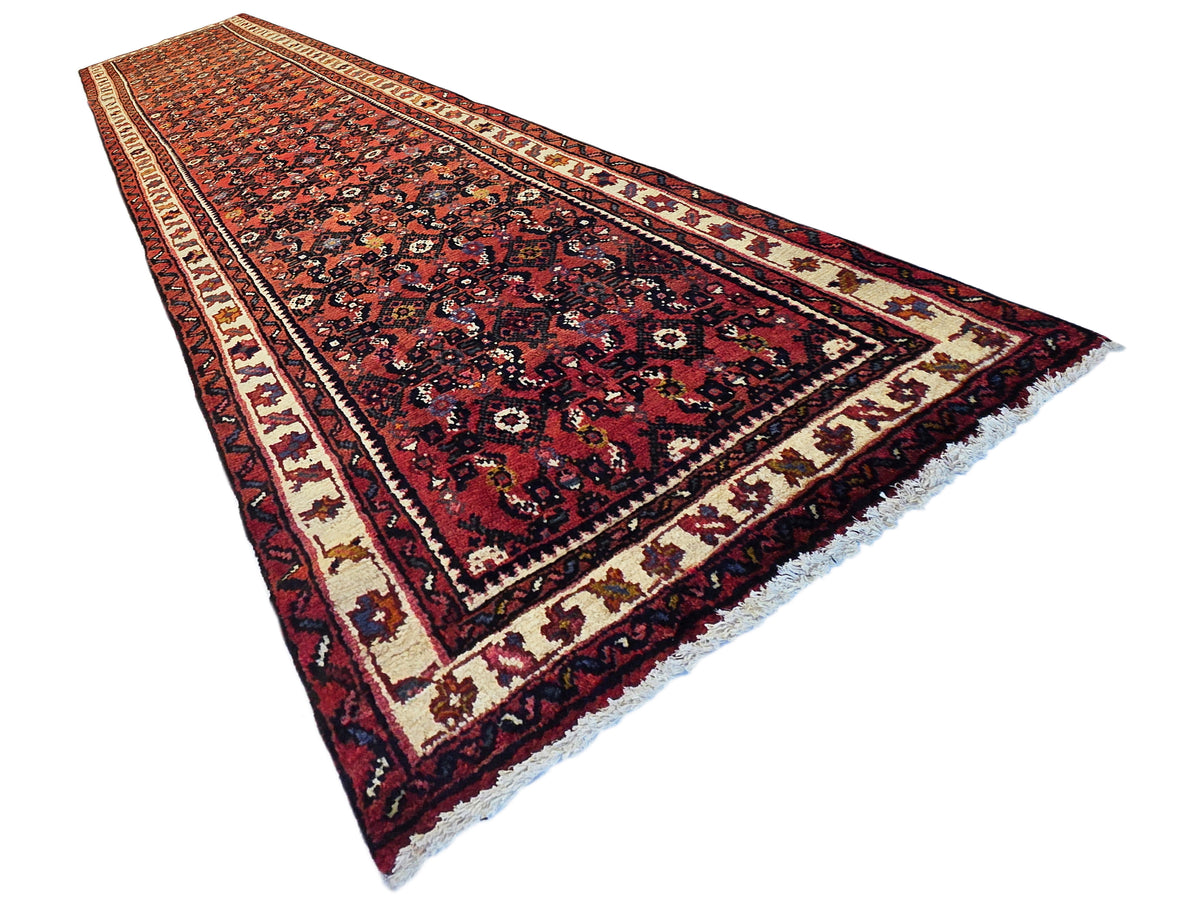 Burgundy runner rug corner view with navy floral pattern and cream border