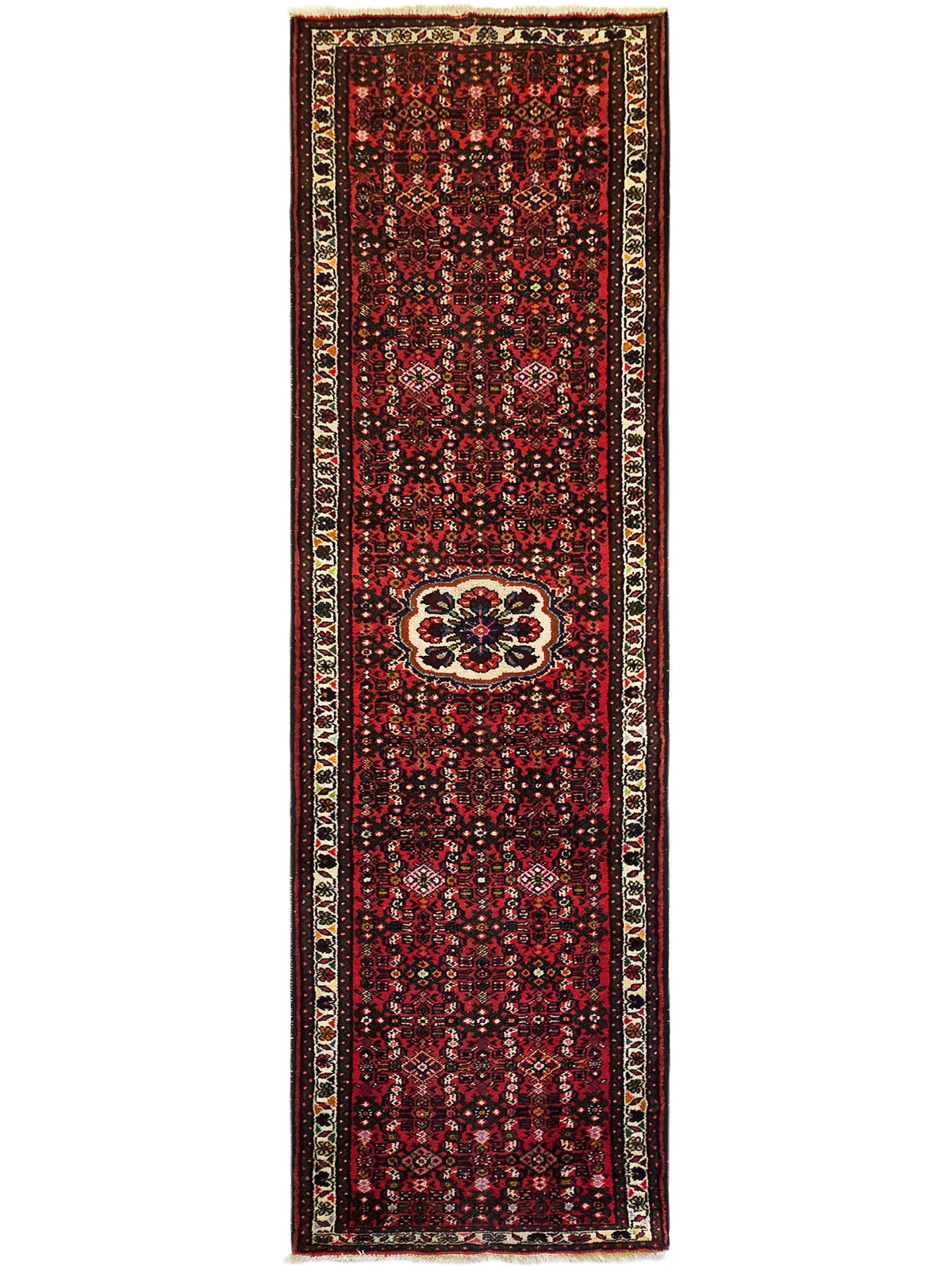 Narrow red runner rug with central medallion panel, dark floral field, cream edging