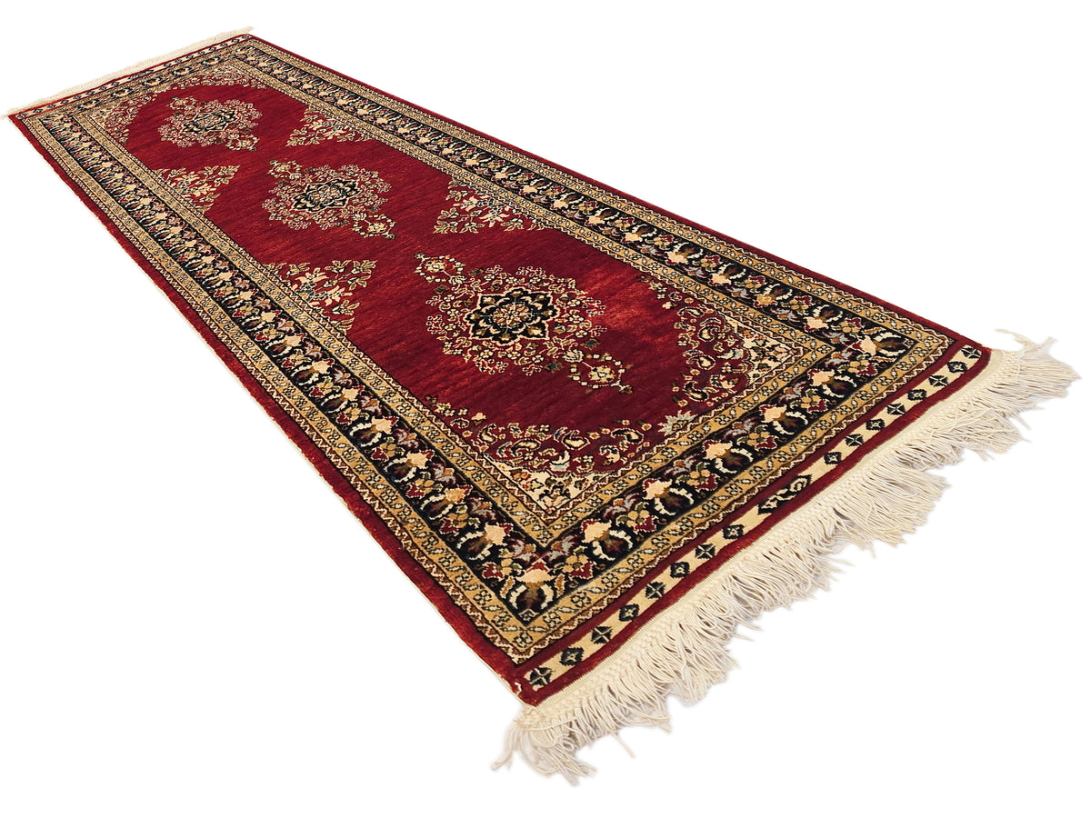 Hereke rug featuring deep red medallions, black and gold borders, and beige fringe