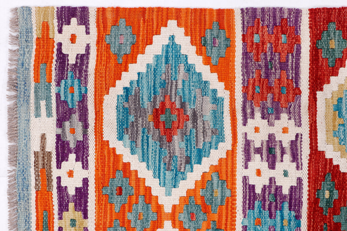 Kilim rug pattern detail with orange, blue, purple, and teal diamond and cross motifs