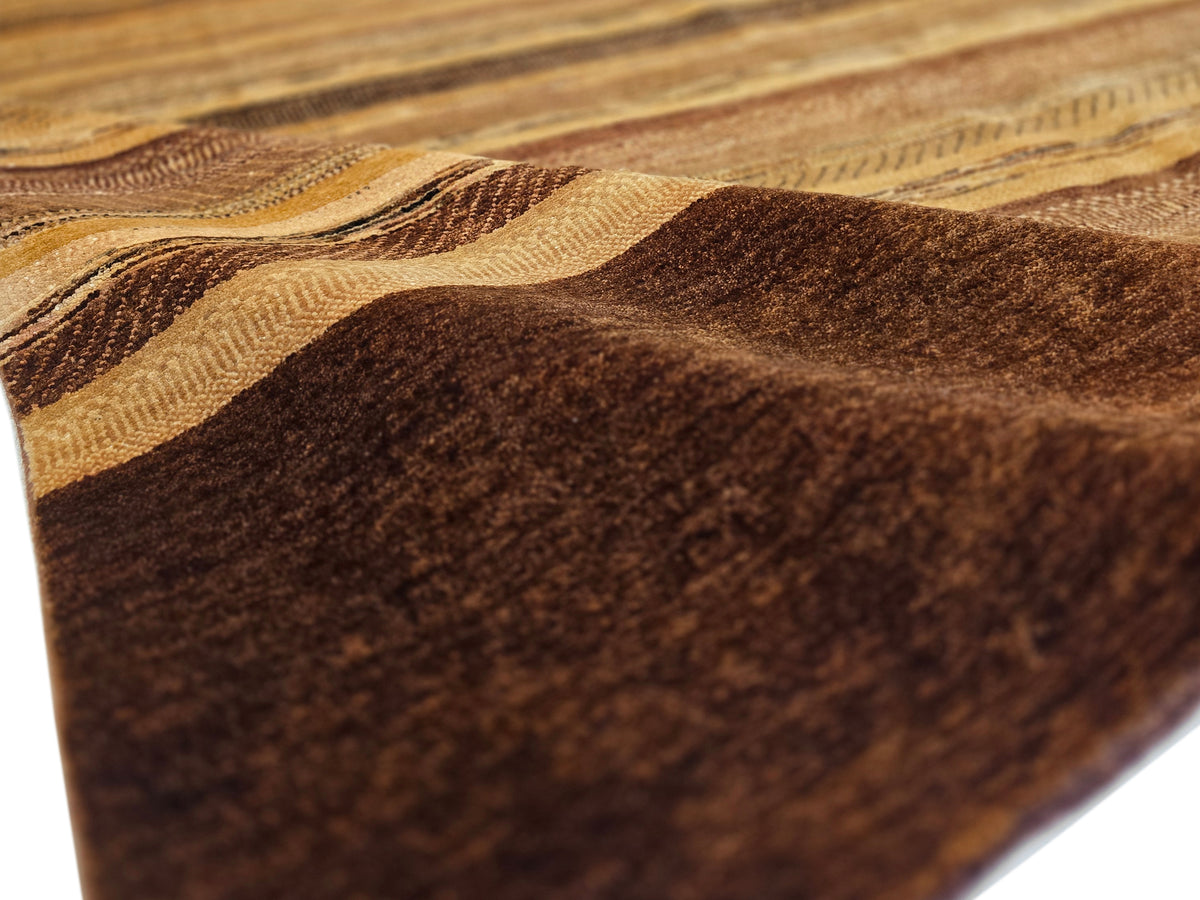 Close-up of rug stripes in tan and dark brown with textured, mottled pile.