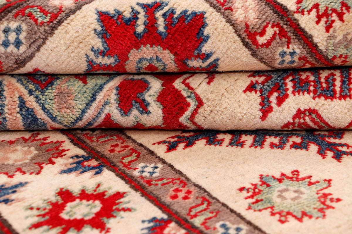 Kazak red rug folded fabric showing texture and repeating floral geometric motifs