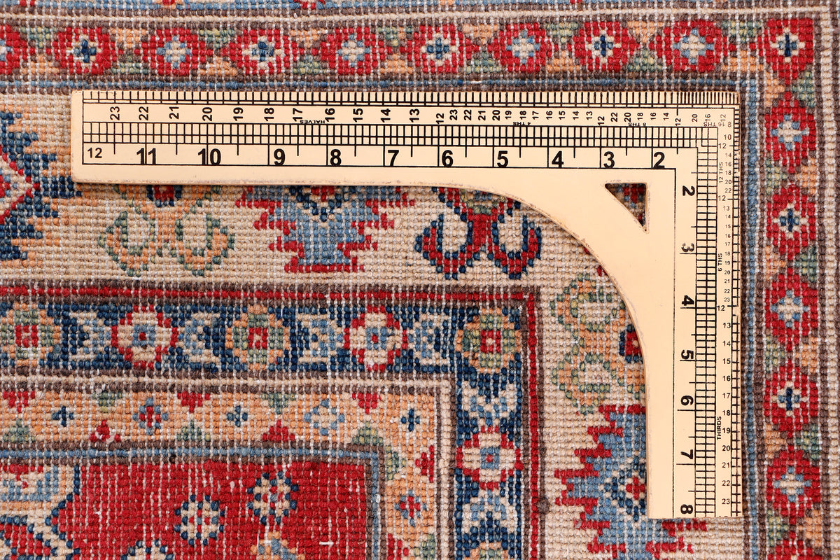 Red and blue patterned rug edge with ruler for size measurement