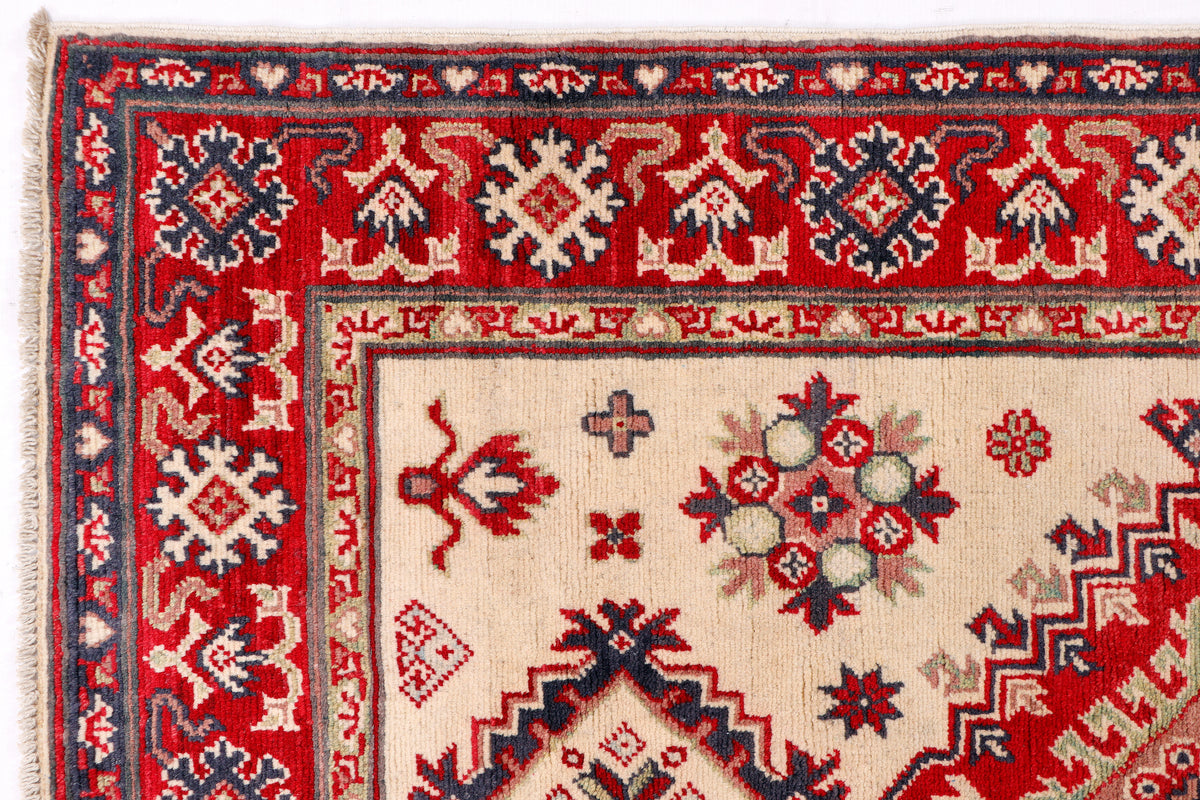 Kazak rug detail: cream panel with red and navy motifs, ornate border