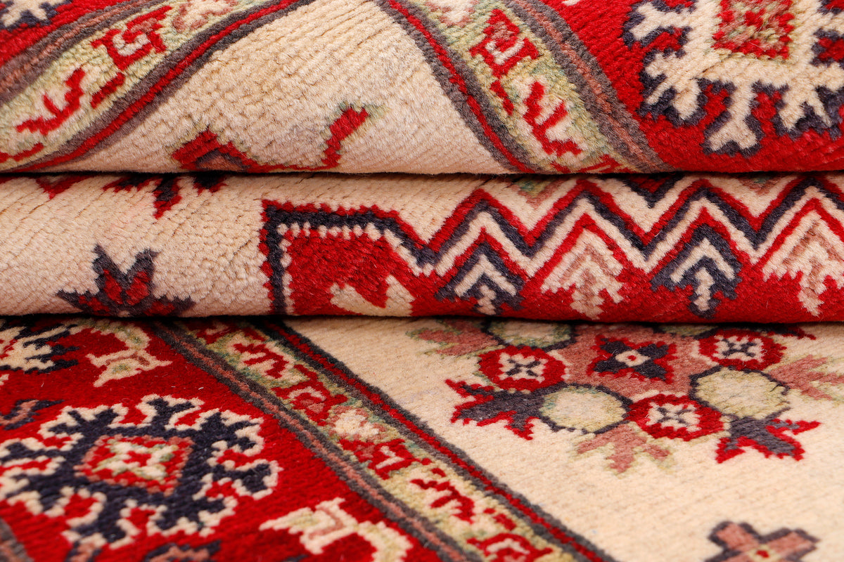Kazak rug edge close-up with folded pile, cream ground and red zigzag pattern