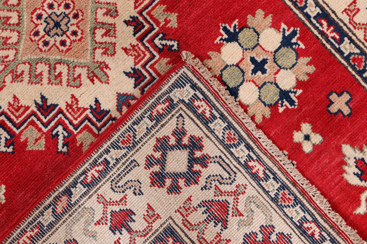 Red rug with cream and navy zigzags and rosette medallions, detailed woven texture