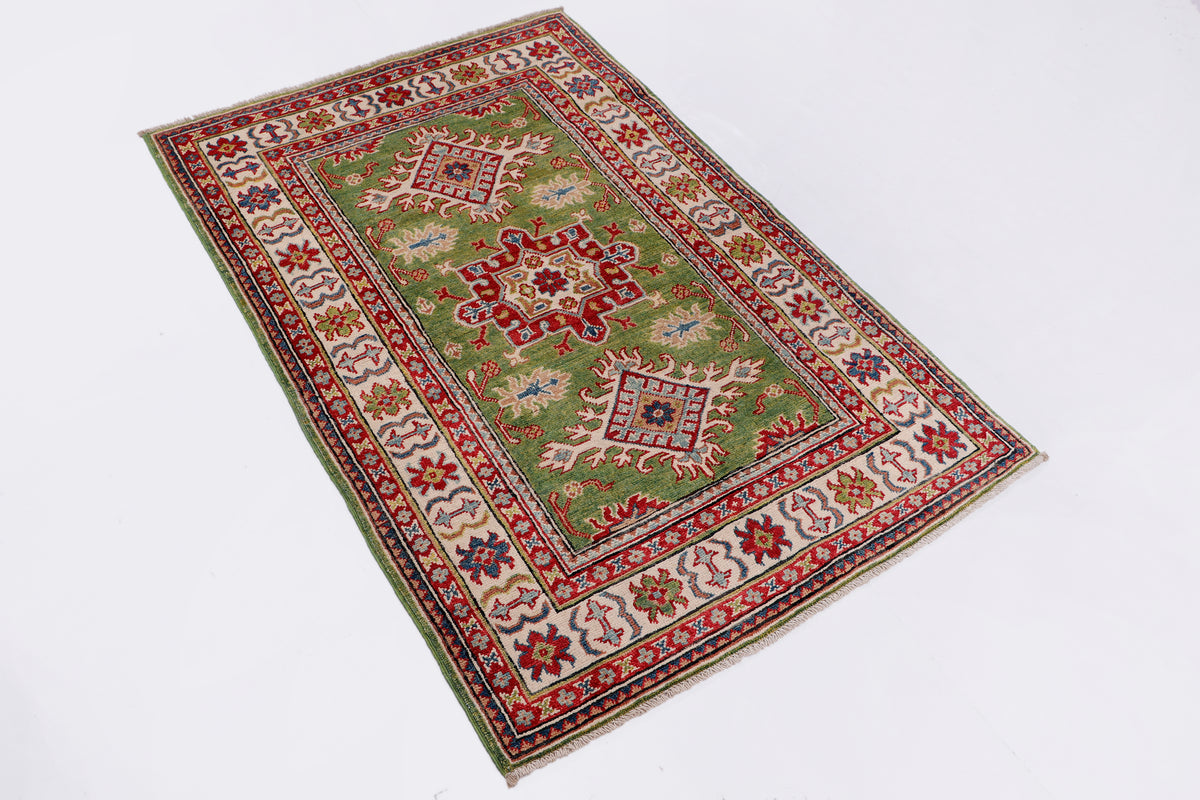 Green rug with red floral medallion, cream corners, and geometric patterned border