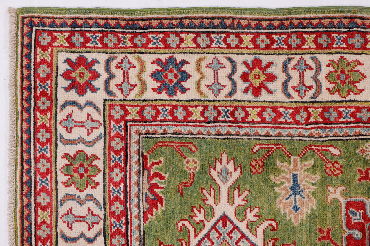 Green rug with red, navy, and cream border pattern and flower and cross motifs