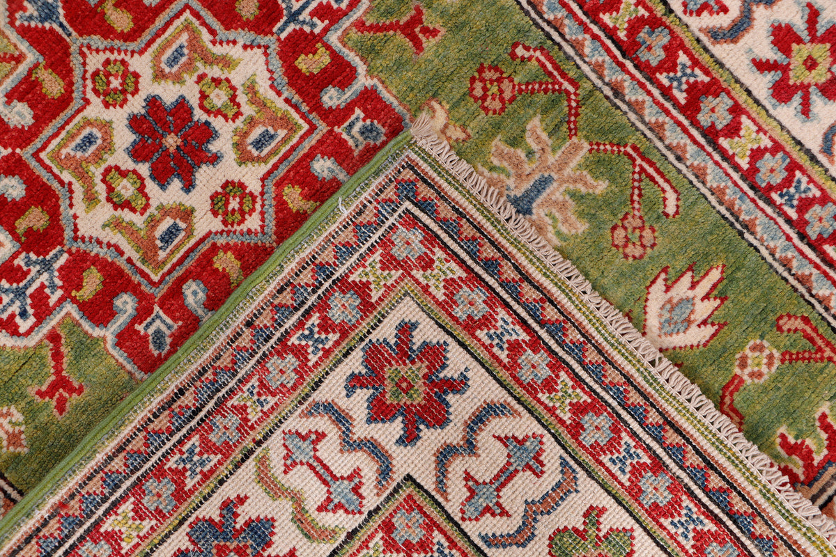Green rug corner with red, blue, and cream lattice motifs and navy-trimmed border