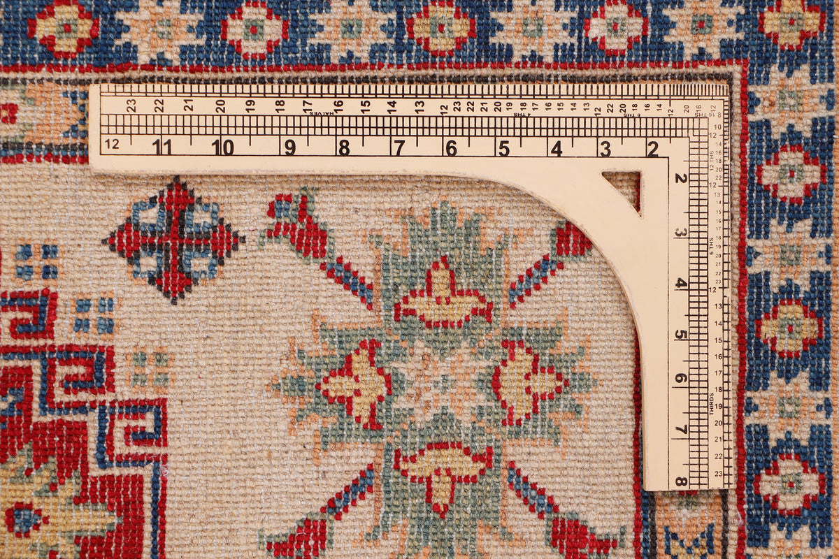 Beige area rug with red and blue geometric medallion pattern, close-up detail