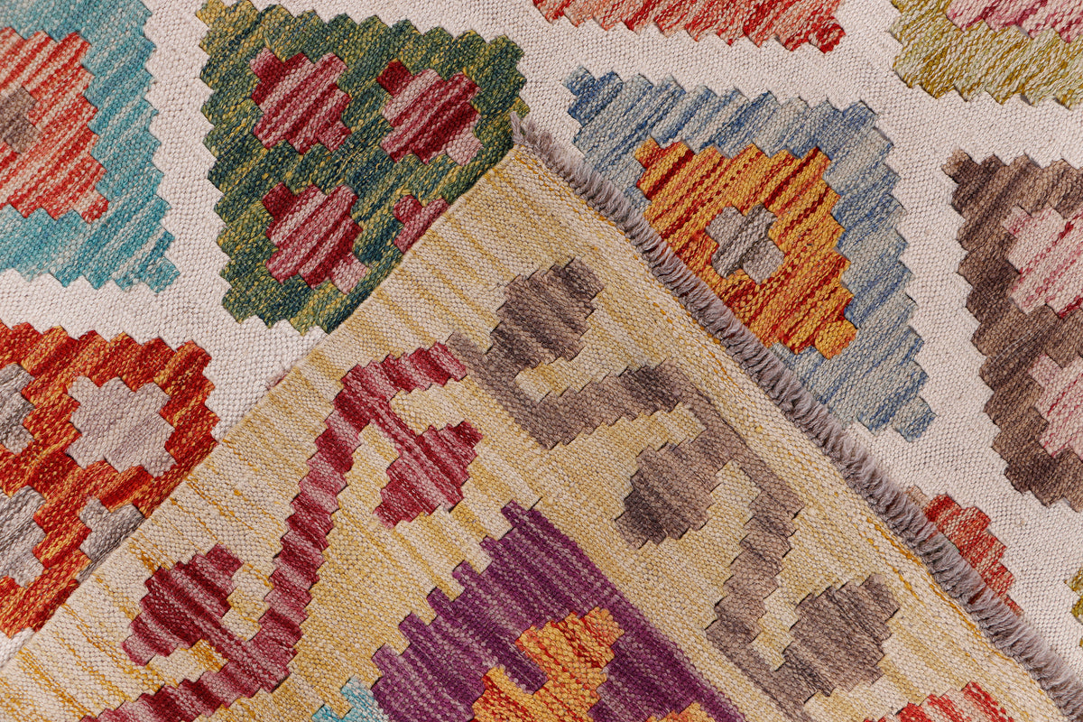 Beige kilim rug corner close-up with multicolor diamond motifs and fringe edge