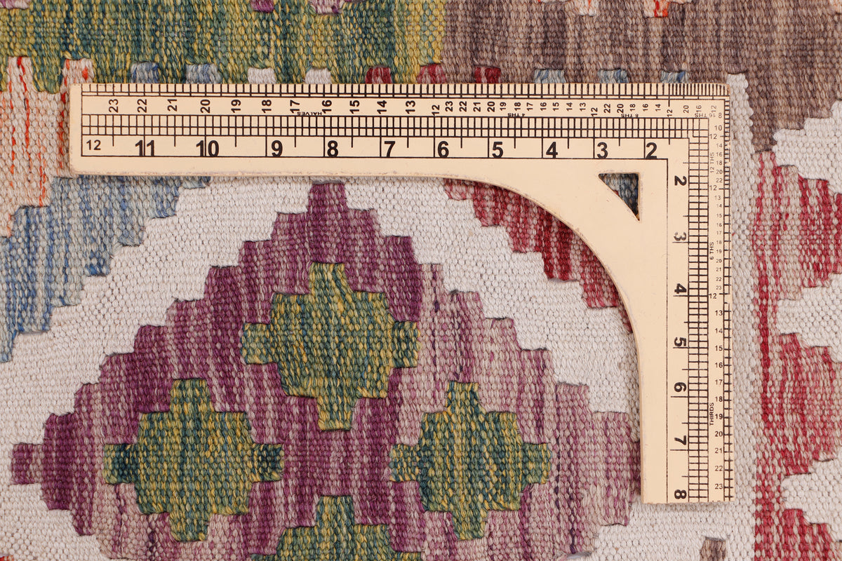 Beige kilim rug detail with geometric motifs and measuring tape along the edge