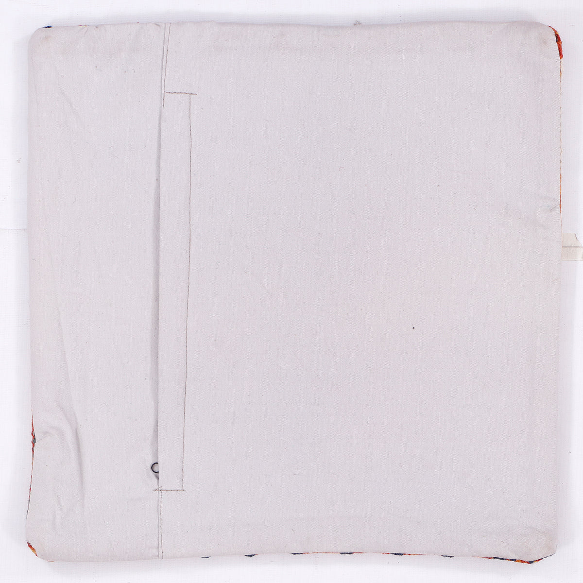 Cream cushion cover reverse side with visible seam lines and faint red stitching.