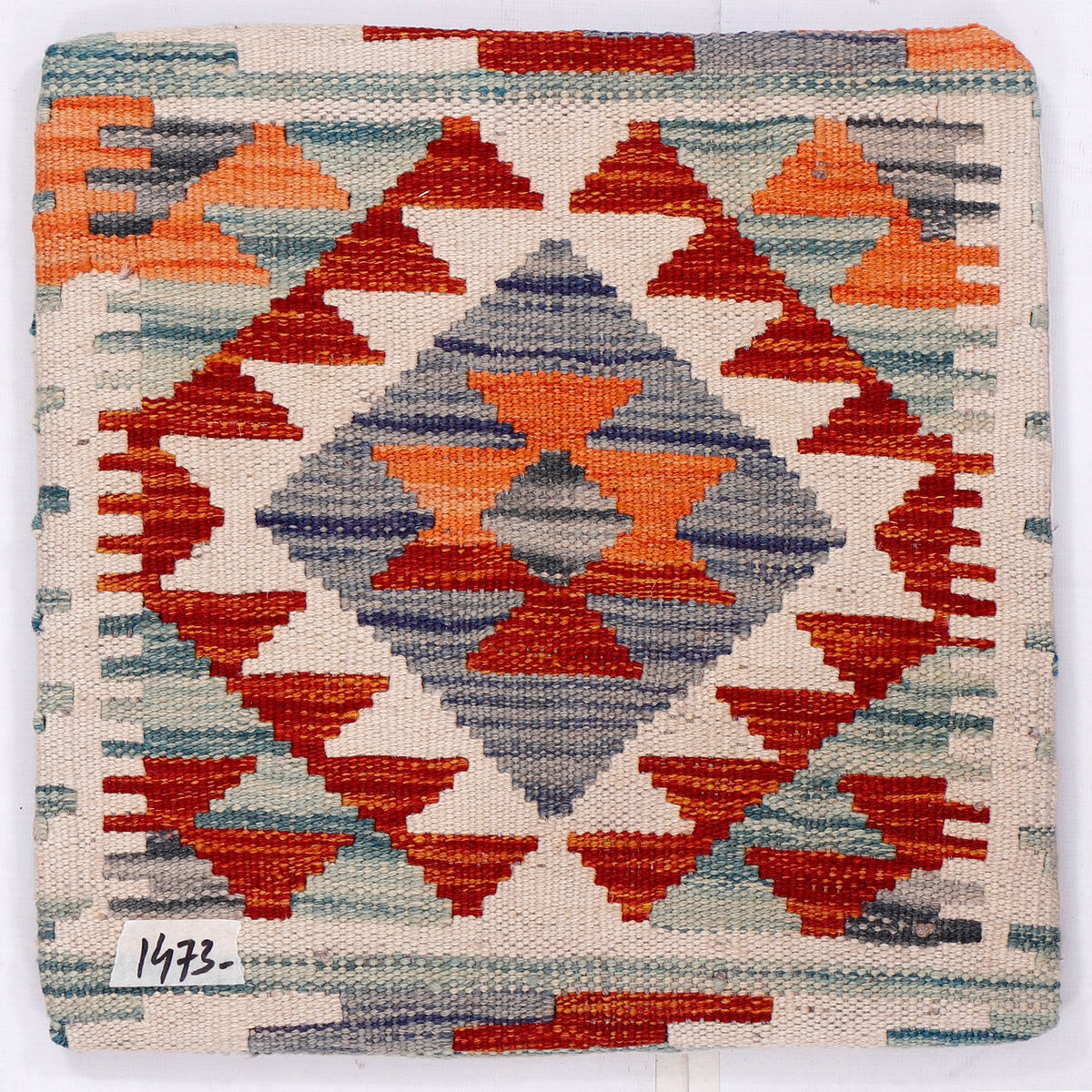 Kilim cushion front close-up, geometric diamonds in orange, red, blue on cream
