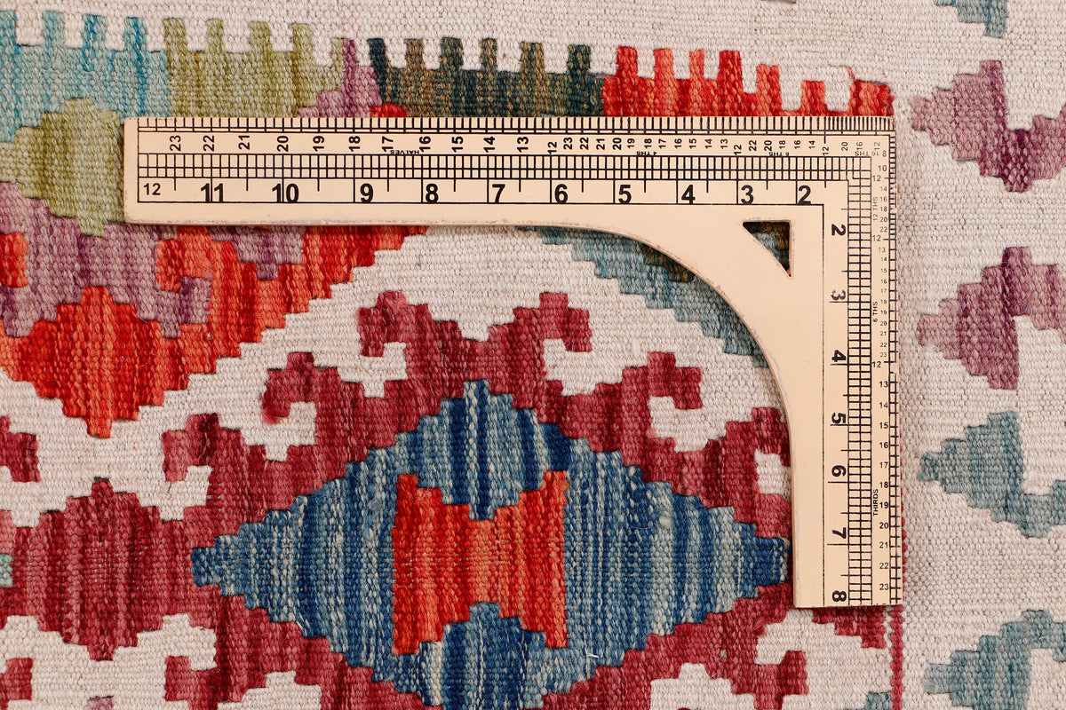 Kilim rug fabric detail with ruler measure over red, blue, and cream motifs