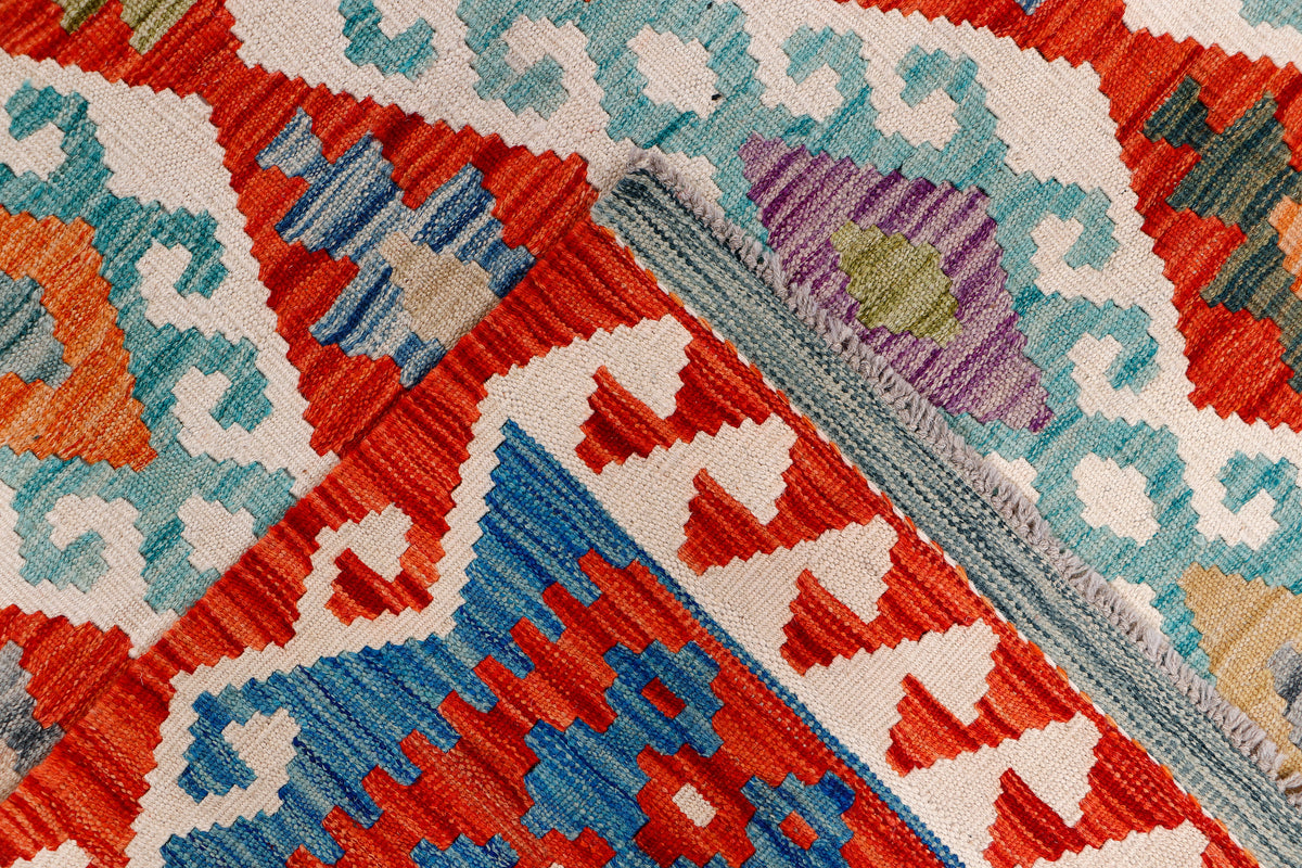 Kilim rug close-up with multicolor diamond and zigzag stitches in red, blue, and teal