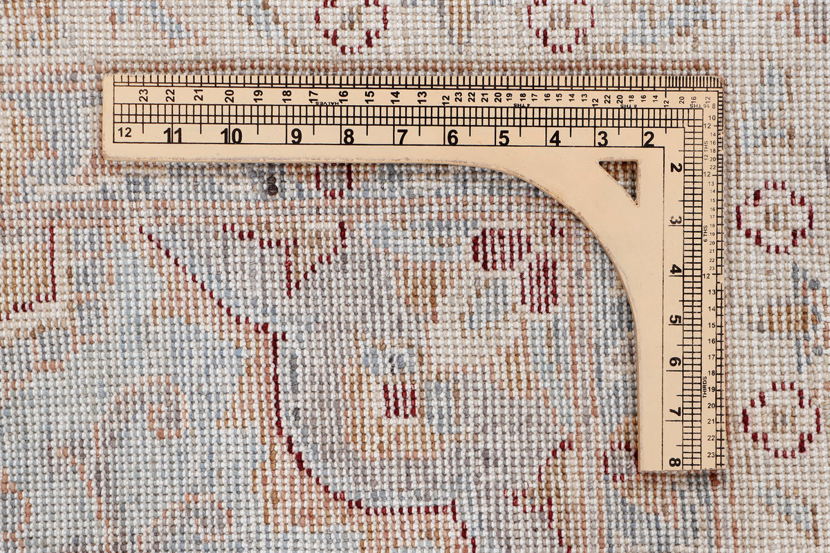 Rug surface close-up with measuring tape and blue floral medallion pattern on beige