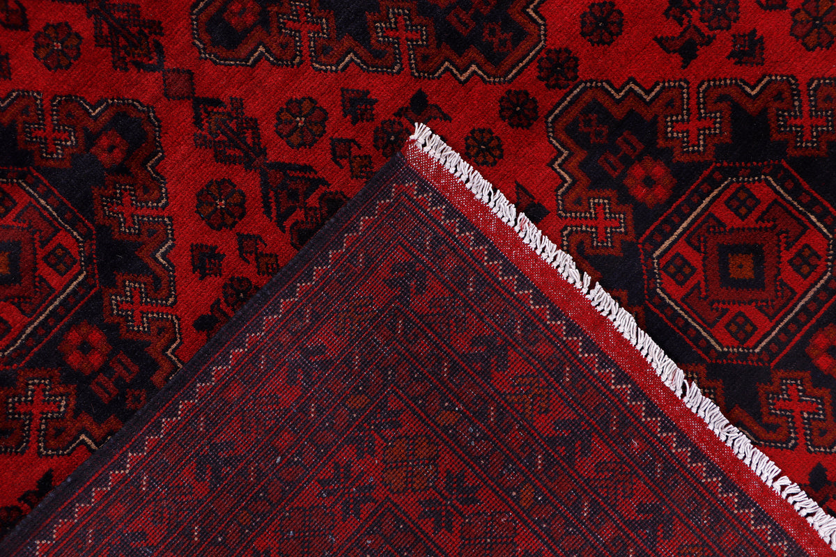 Red rug corner with fringe detail and layered geometric pattern