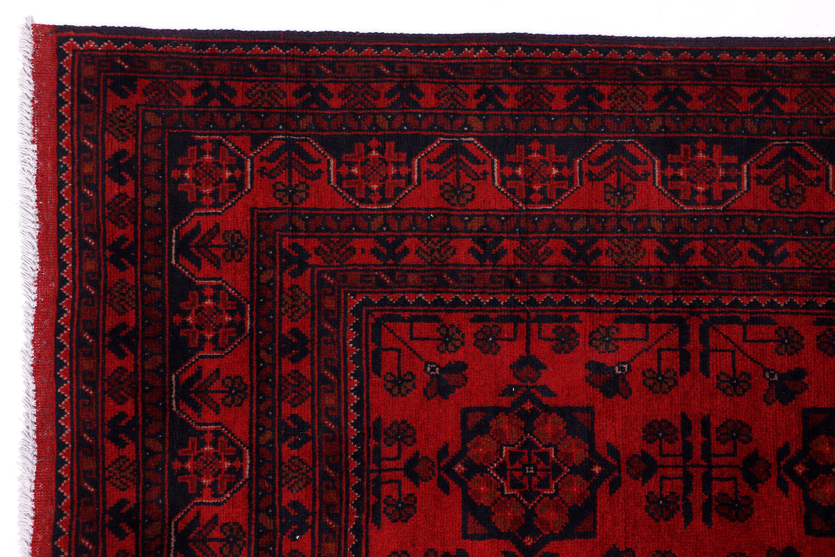 Red rug close-up with dark border and central medallion-like pattern