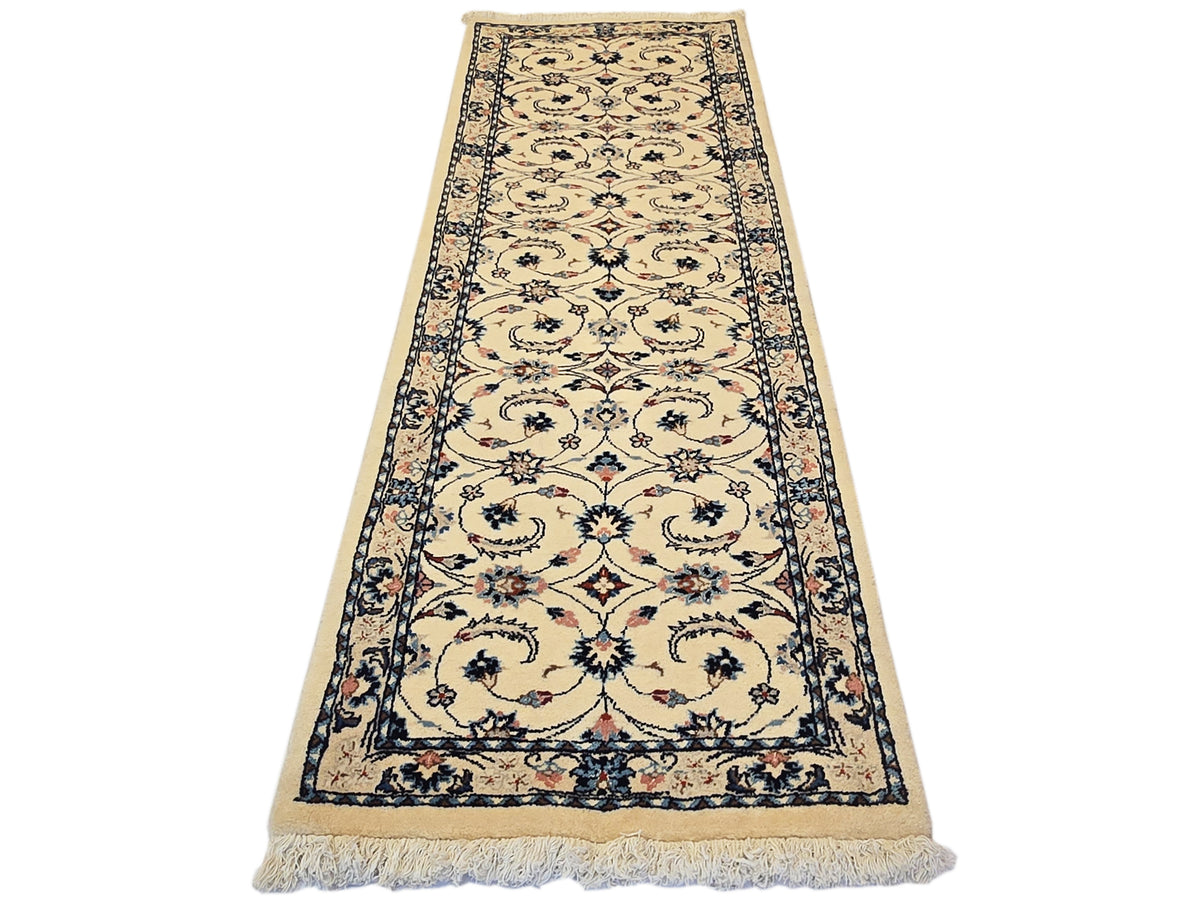 Long runner rug with beige field, navy floral border, and short fringe along edges.