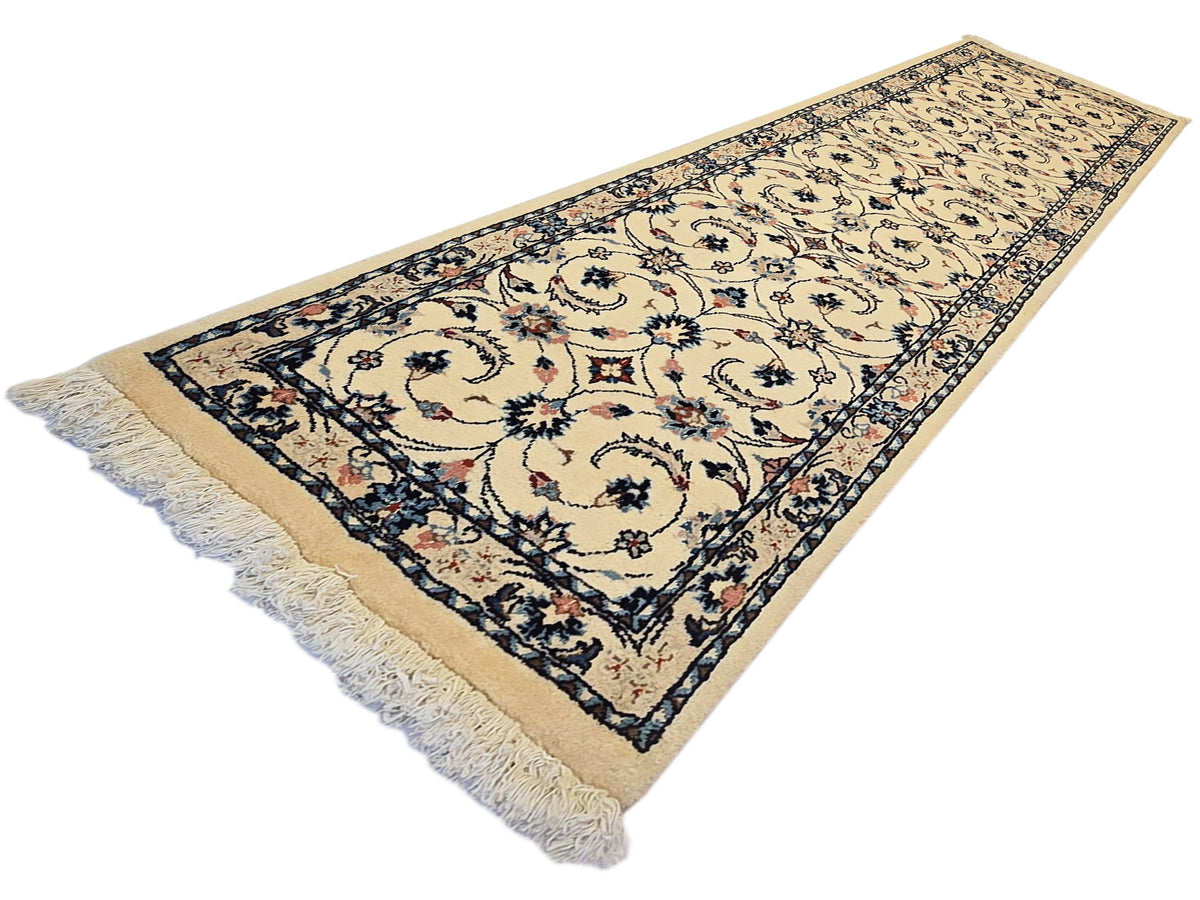 Khorasan-style runner rug with beige field, dark blue border, floral medallion pattern, fringe.