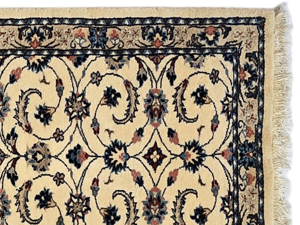 Close-up of floral medallion pattern on beige runner rug with dark blue border and fringe.