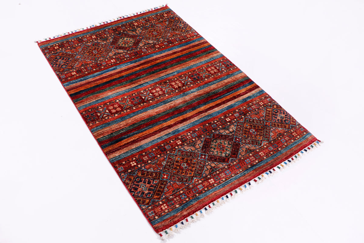 Geometric rug in red, blue, and orange with fringed edges, angled view