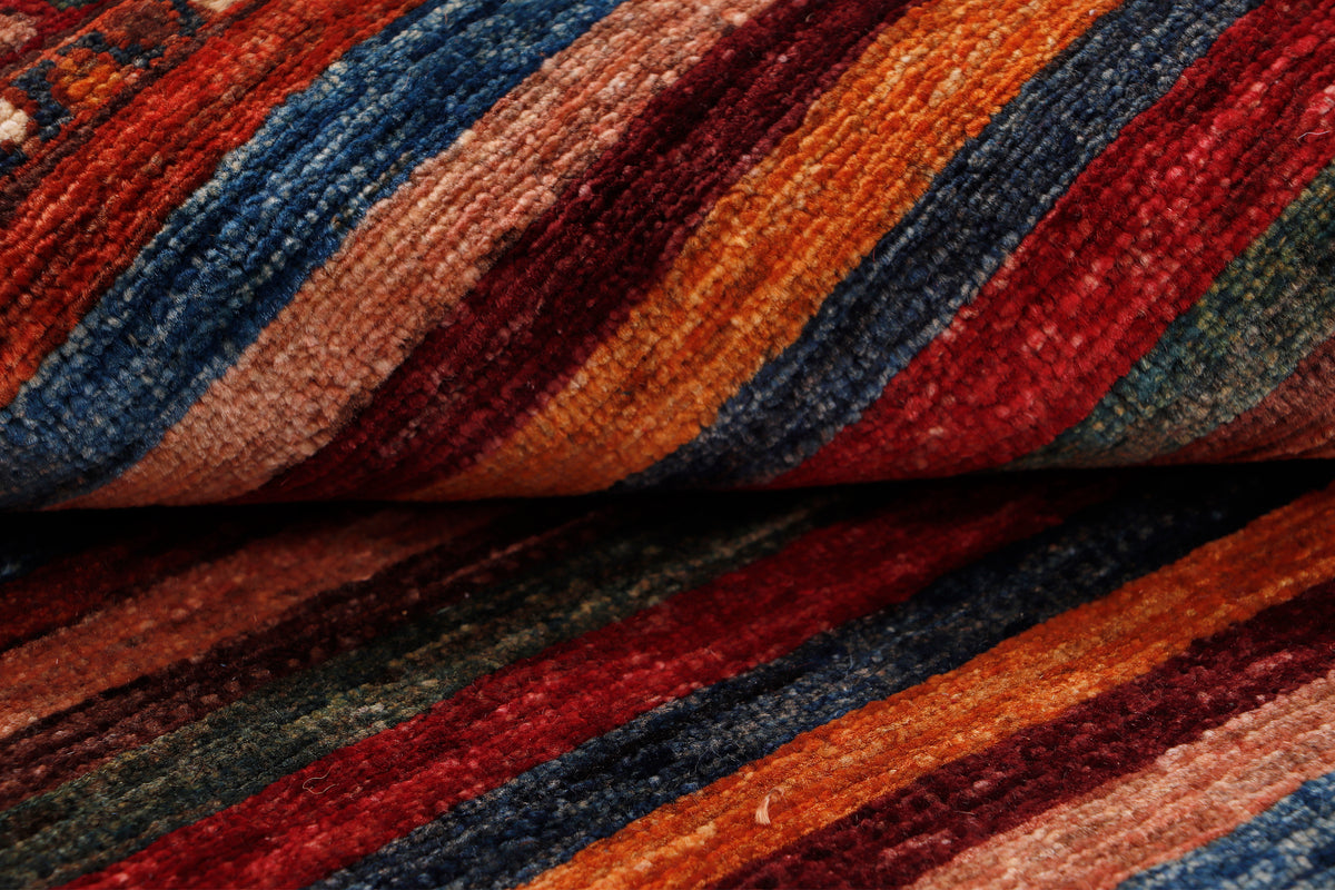Close-up of red rug showing woven stripes and diamond textures with dark blue accents