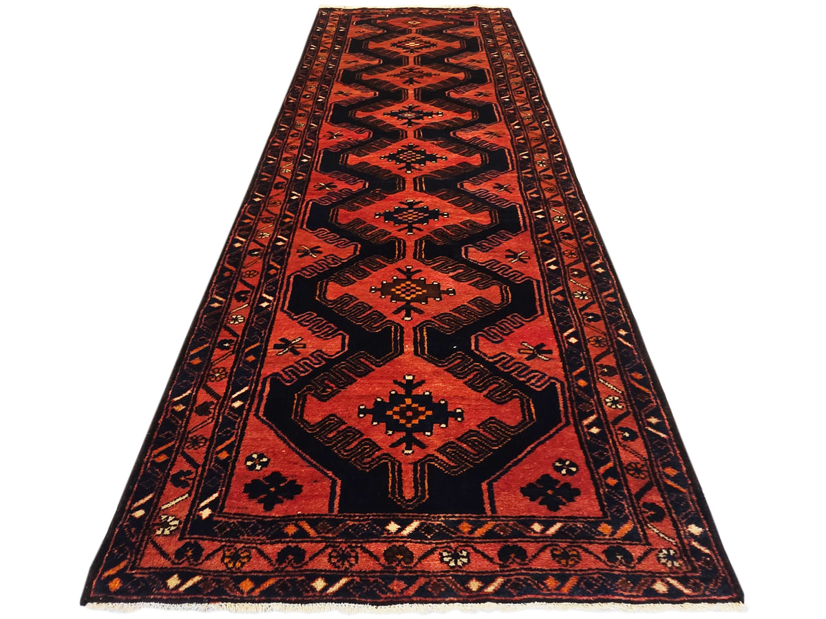 Red and black geometric patterned area rug with border and central medallion.