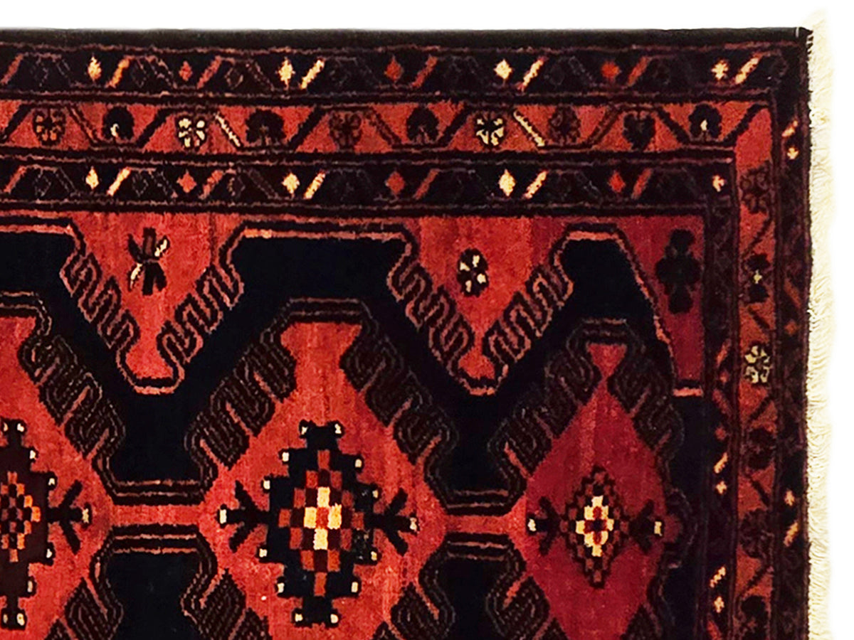 Close-up of red and black geometric rug with diamond motifs and patterned border.