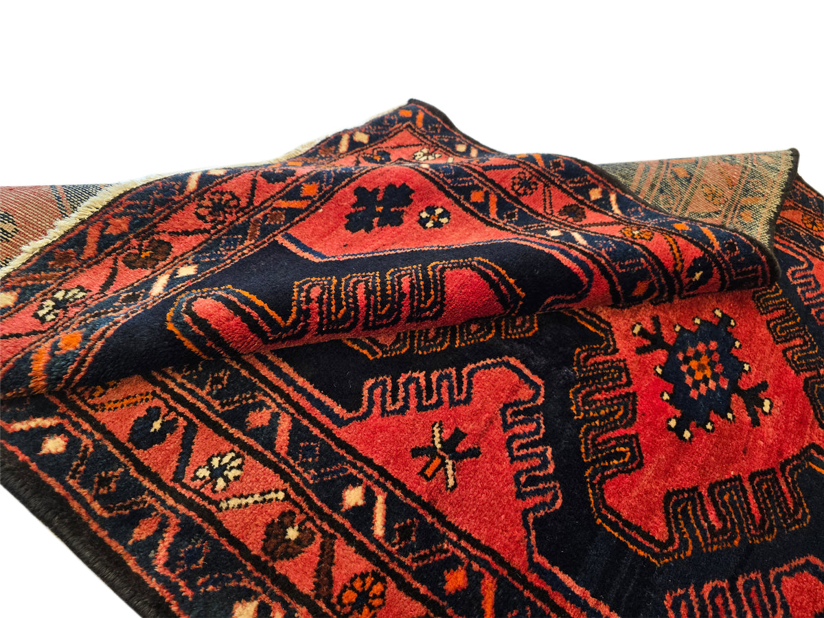 Red and dark geometric area rug with central medallion and short fringes on edge.