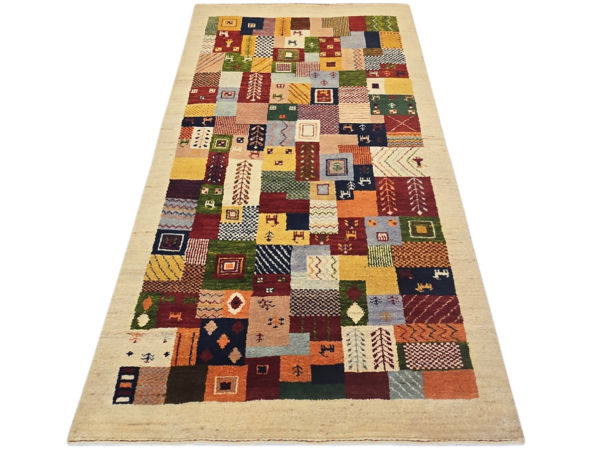 Long Loribaft rug with multicolor patchwork blocks and small geometric motifs on beige.