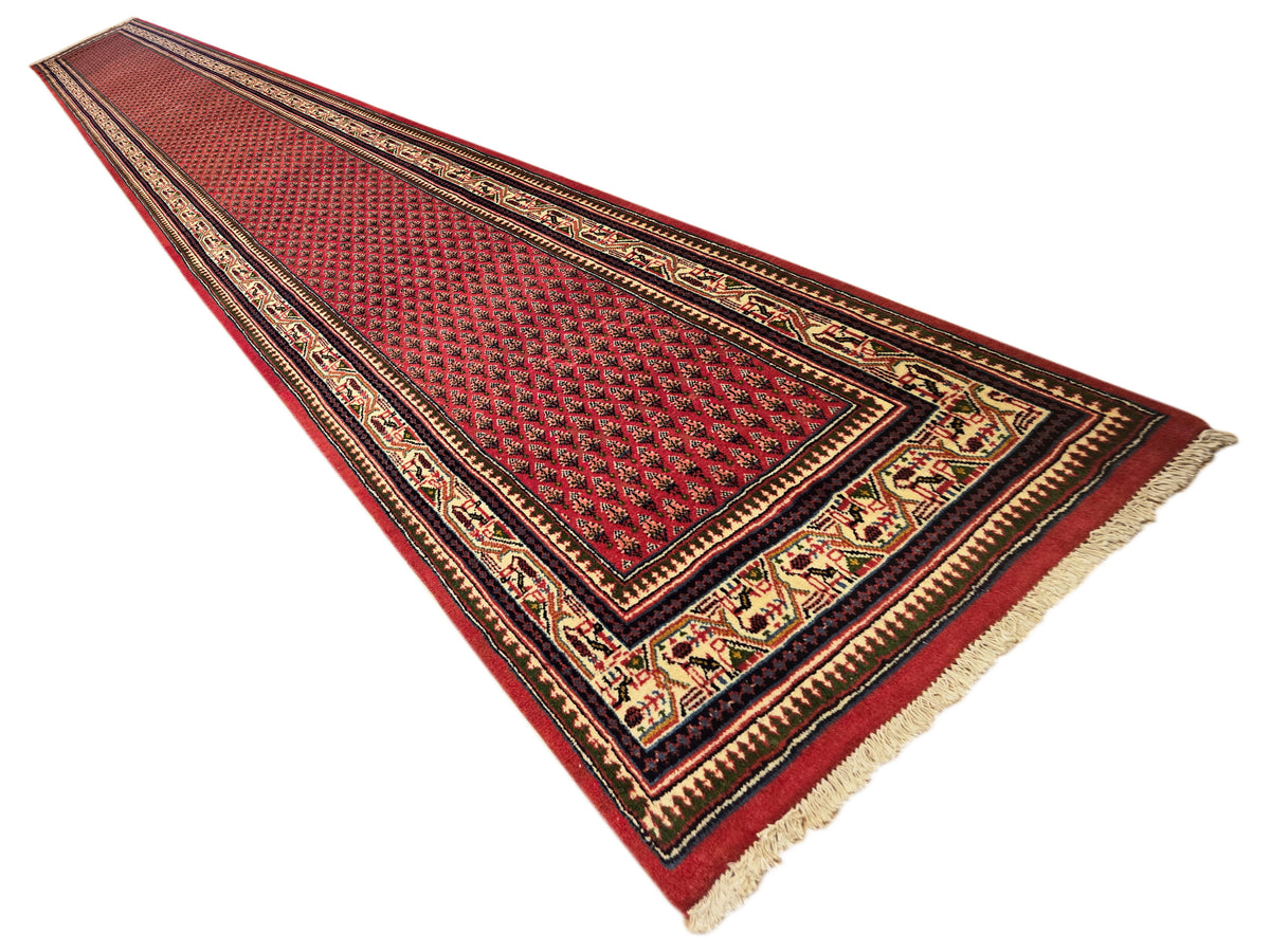 Red patterned runner rug with dark border, ornate center medallion, and fringe