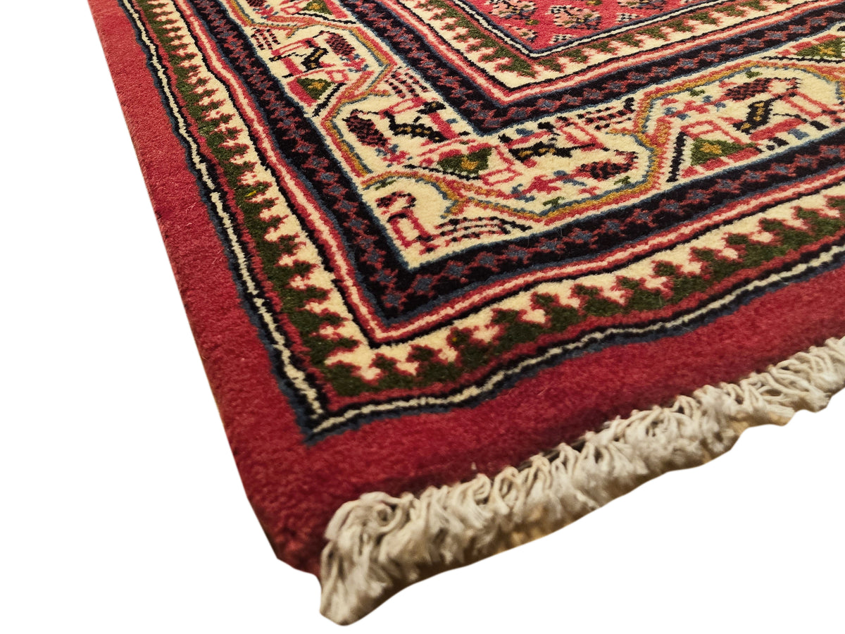 Red runner rug edge with short cream fringe and multicolor geometric banding
