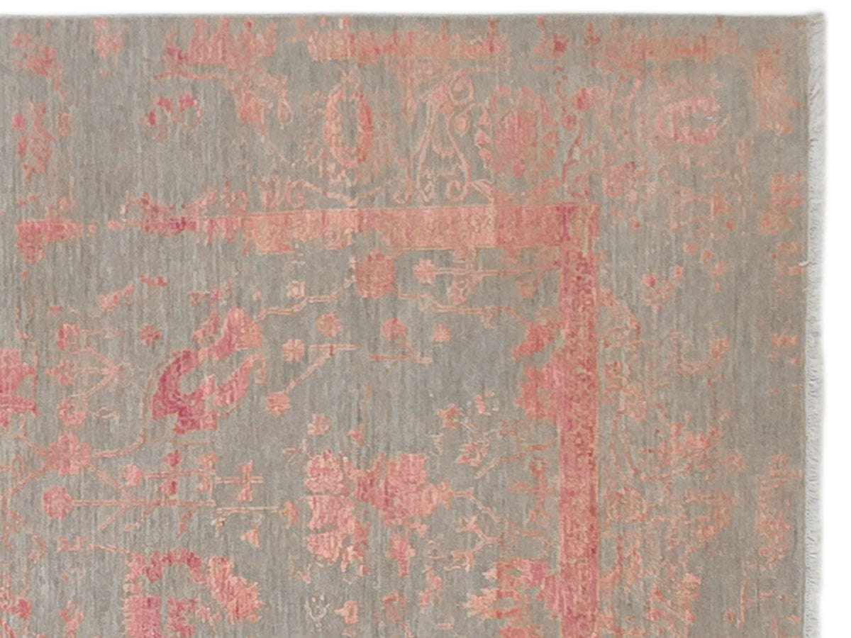 Close-up of modern rug surface: gray texture with faded pink ornate pattern