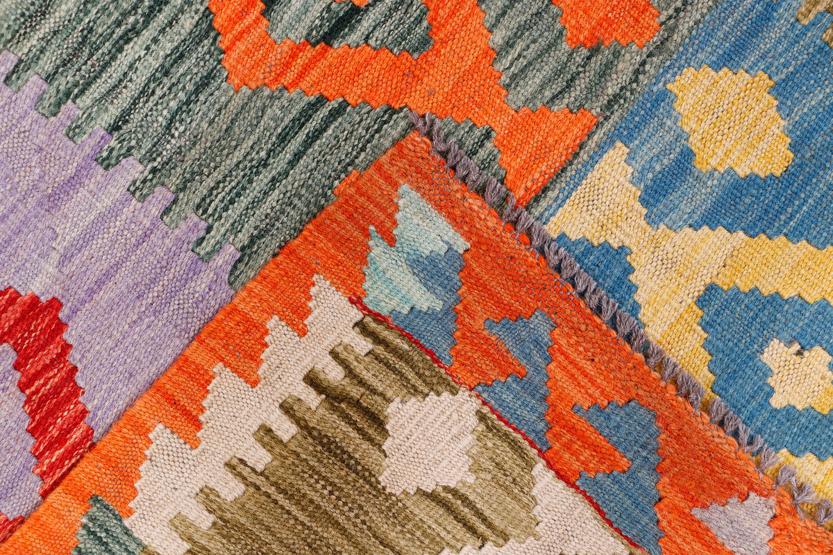 Kilim rug detail with stitched geometric motifs in orange, blue, beige, purple and gray